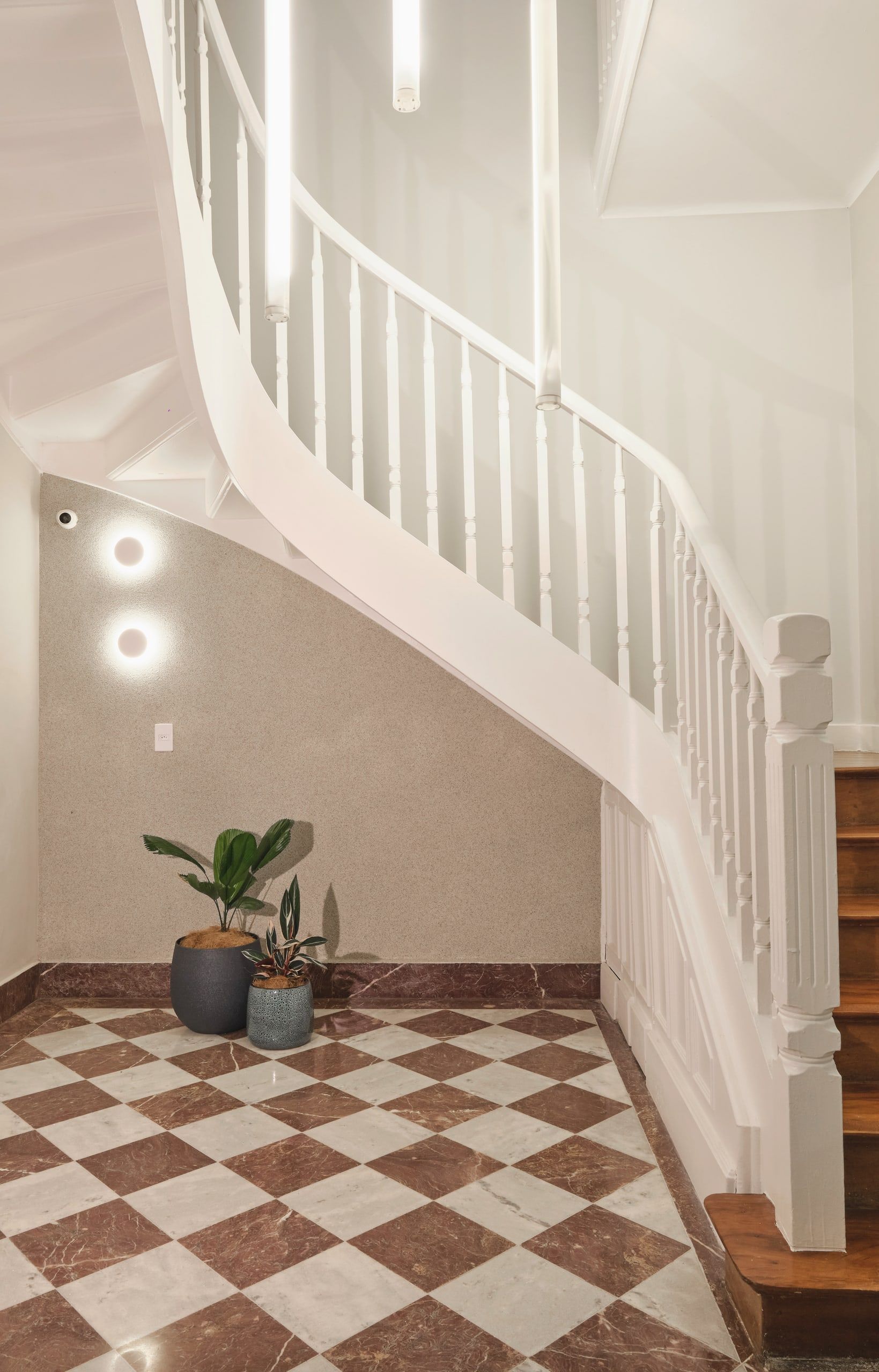 Escada em curva da casa da Phen, sobre piso xadrez